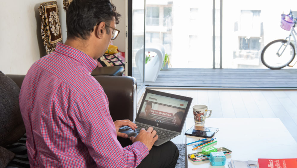 Single Parent sitting on a sofa with a laptop on their lap, searching for advice on the Gingerbread website
